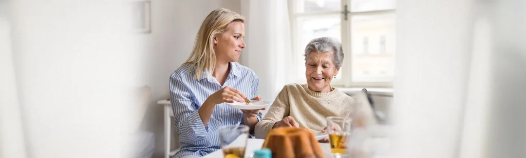 Junge Frau mit alter Frau beim Kuchen essen