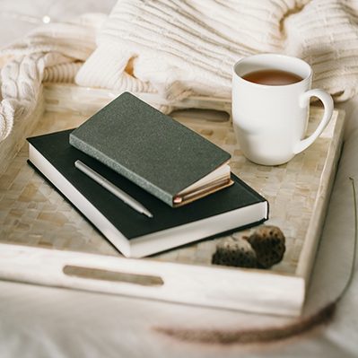 Tablet mit Buch und KAffe auf einem Bett